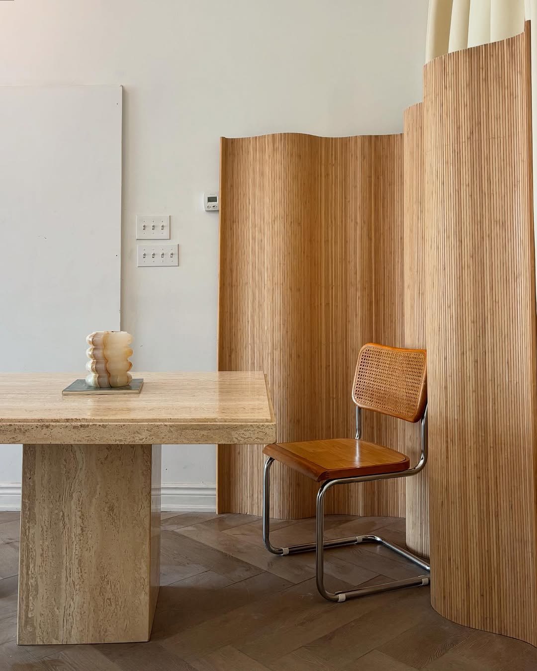 Dining room with travertine table, cane chairs and warm daylight