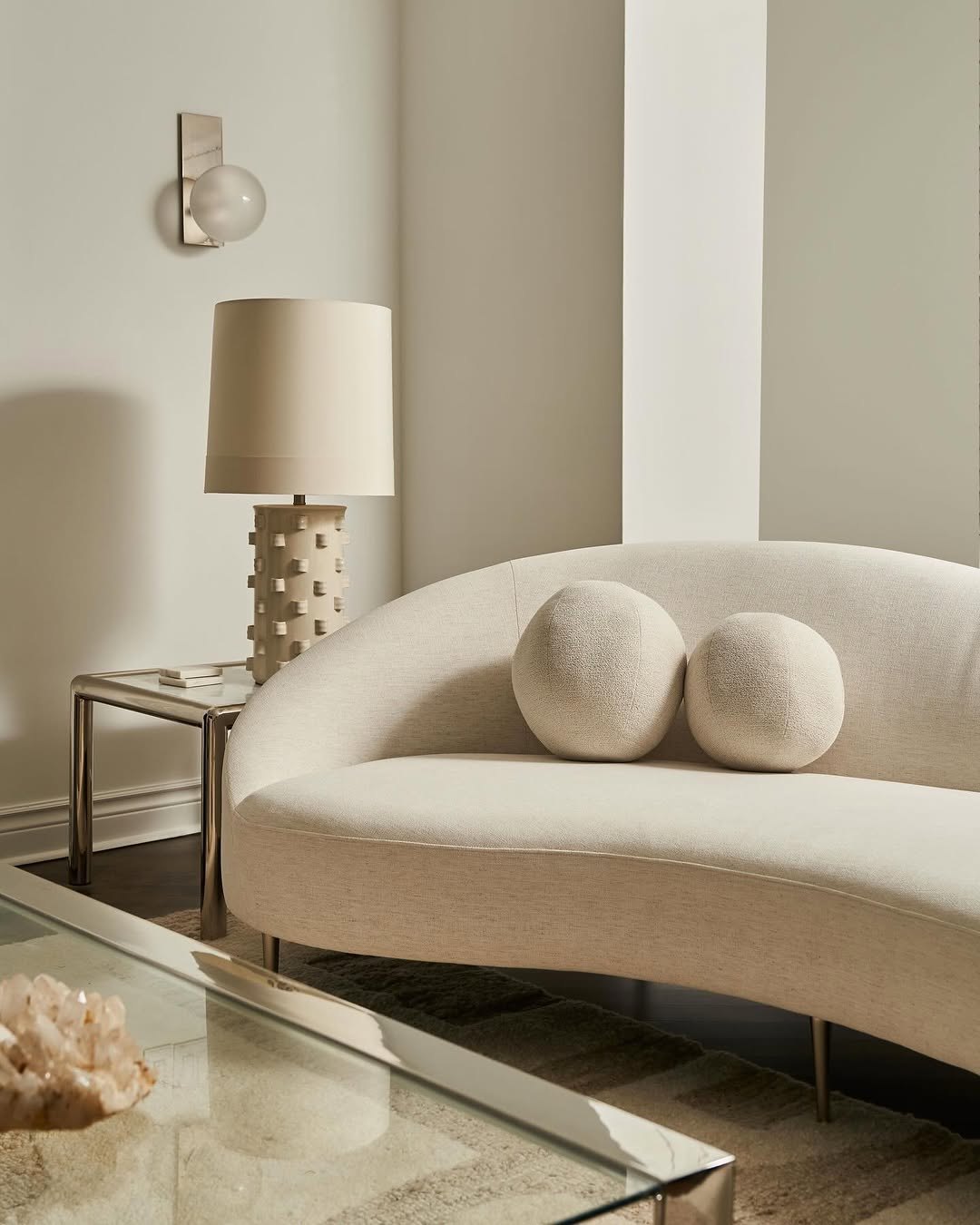 Living room with a curved bouclé sofa, travertine table and warm plaster walls